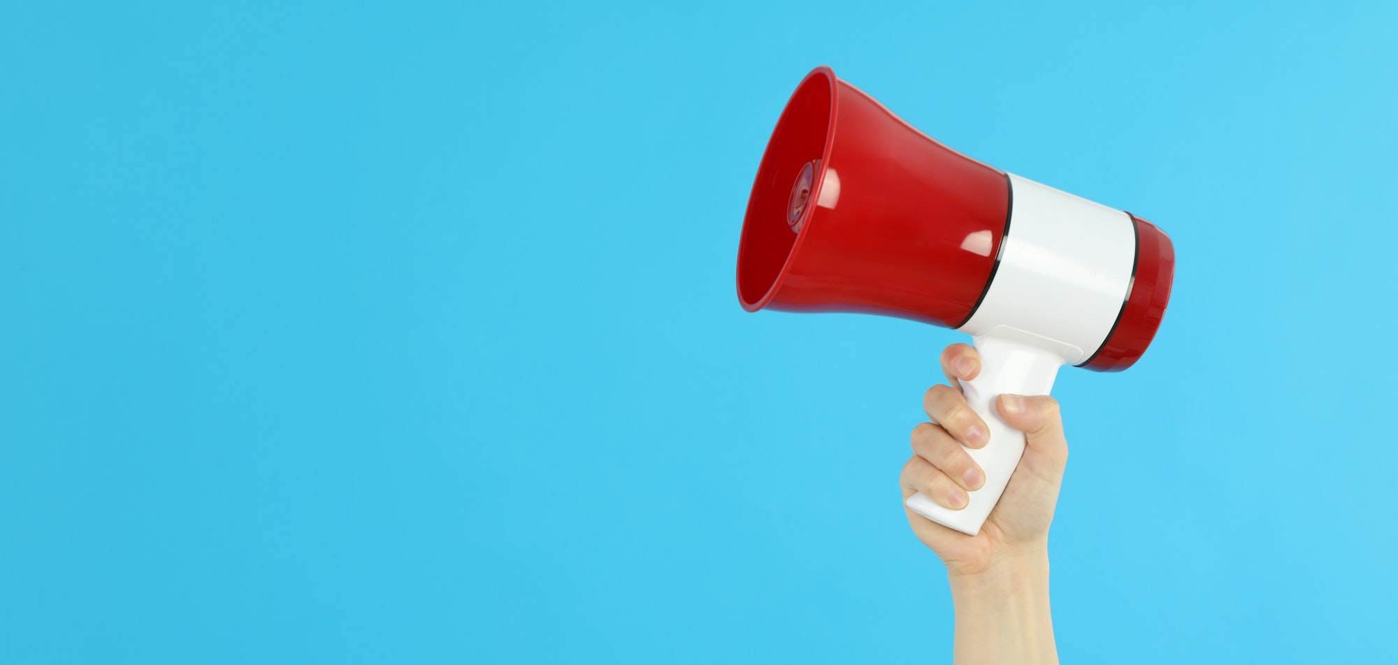 Female hand holds megaphone on blue background